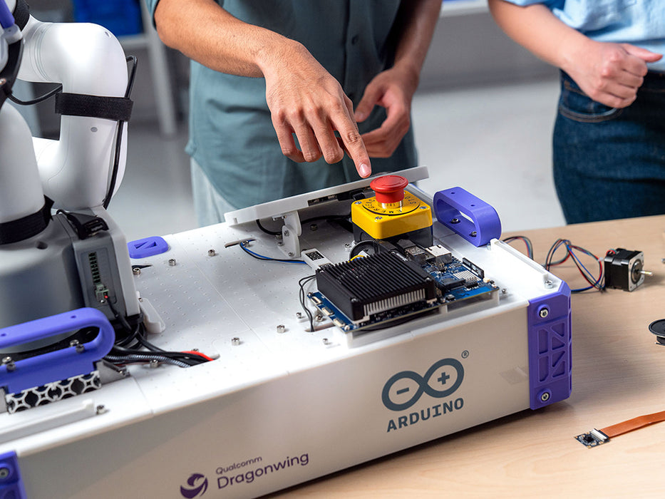 Lifestyle context shot of the Arduino VENTUNO Q, showing it mounted on a robotic arm workstation being adjusted by two people.
