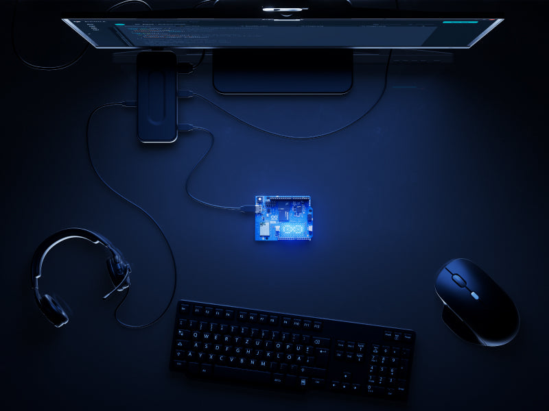 Top-down view of a dark workstation showcasing 'Arduino UNO Q Standalone mode'. The Arduino UNO Q board is the central controller, connected directly to a monitor, keyboard, mouse, and headphones via a USB hub, functioning as a primary computer.