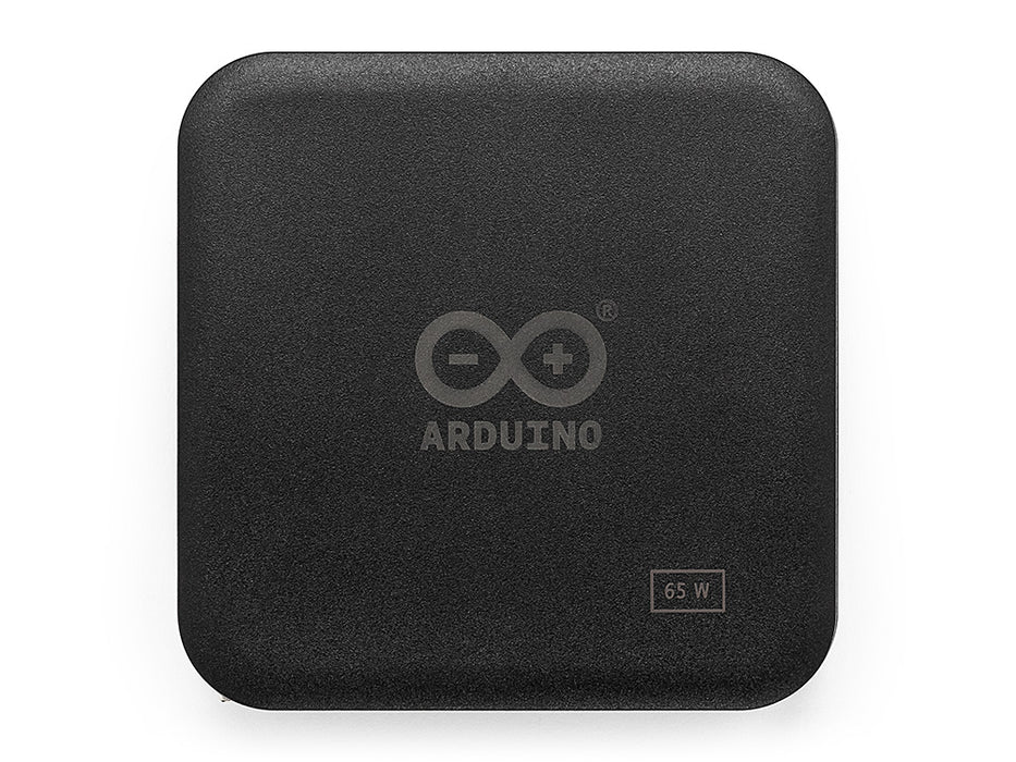 Direct top-down view of the black, square Arduino 65W power adapter with rounded corners, showing the central logo.